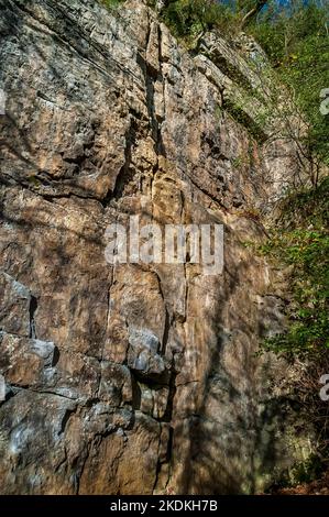 Hohe Kalksteinfelsen, teilweise bebaut, mit Höhleneingängen und künstlichen Eingängen für Bleiminen, in Middleton Dale, Stoney Middleton, Peak District. Stockfoto