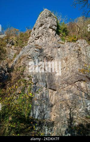 Hohe Kalksteinfelsen, teilweise bebaut, mit Höhleneingängen und künstlichen Eingängen für Bleiminen, in Middleton Dale, Stoney Middleton, Peak District. Stockfoto