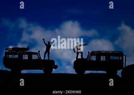 Miniatur-Spielzeuge zweier Männer feiern triumphierend am Bergkonzept. Stockfoto