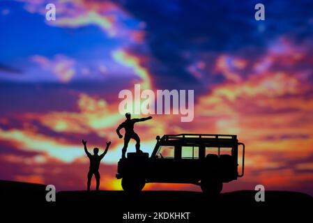 Miniaturspielzeuge zweier Männer feiern triumphierend beim Bergkonzept bei Sonnenuntergang oder Sonnenaufgang. Stockfoto