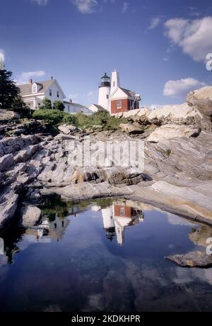 Der Leuchtturm Pemaquid spiegelt sich in einer nahe gelegenen Pfütze wider, die in dem festen Granit, der die Küste von Maine bildet, gefangen ist. Stockfoto