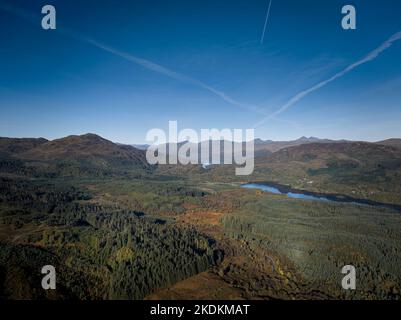 Luftaufnahme des Duke's Pass mit der Straße, die sich an einem sonnigen Herbsttag durch die Forstwirtschaft nach Loch Achray und Loch Katrine in den Trossachs schlängelt. Stockfoto