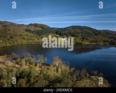 Luftaufnahme von Loch Achray in den Trossachs mit Tigh More Timeshare-Schloss und -Gelände an einem wunderschönen Herbsttag. Stockfoto