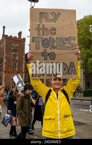 Junge Frau protestiert gegen die Flüchtlingspolitik der konservativen Regierungen mit einem Plakat: „Fliege die Tories nach Ruanda“. Stockfoto