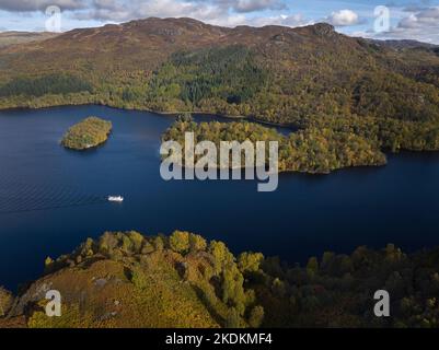 Aus der Vogelperspektive sehen Sie eine Bootstour auf dem Loch Katrine in den Trossachs, die an einem wunderschönen Herbsttag an Ellen's Isle und Coire Na Uruisgeanon vorbeifährt. Stockfoto