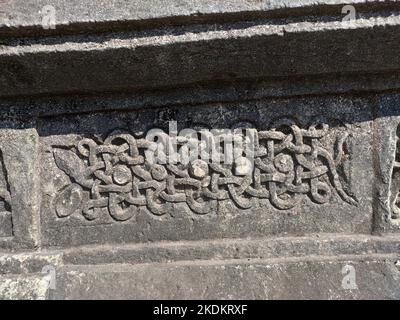 Eine Nahaufnahme einer Schlangenschnitzerei an der Wand des Halebidu-Tempels, die Hoysala-Kunst mit komplizierten Schuppen, gewickelter Form und detaillierter Handwerkskunst zeigt. Stockfoto