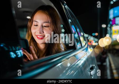 Asiatische Geschäftsfrau pendelt vom Büro in Taxi Rücksitz mit Handy auf der Straße Stockfoto