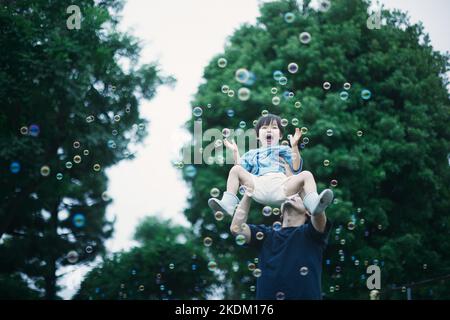 Japanisches Kind, das an einem regnerischen Tag draußen spielt Stockfoto