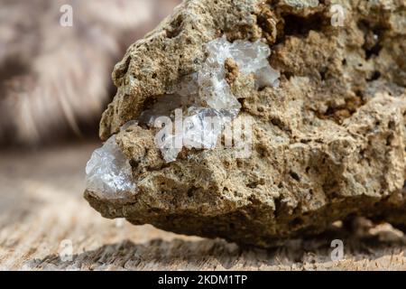 Makroaufnahme von klarem Quarzkristall auf rohem Stein auf Holzhintergrund Stockfoto