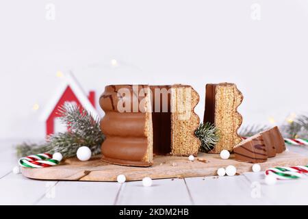 Schneiden Sie den traditionellen, mit Schokolade verglasten, geschichteten Winterkuchen „Baumkuchen“ vor der saisonalen Dekoration auf Stockfoto