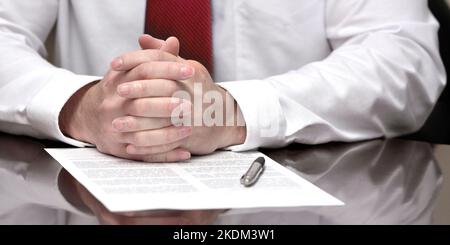 Geschäftsmann am Schreibtisch mit Stift und Handgesten Stockfoto