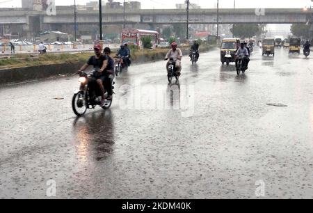 Hyderabad, Pakistan, 07. November 2022. Pendler fahren am Montag, den 07. November 2022, während des ersten Regenguß der Wintersaison in der Gegend von Teen Hatti in Karachi durch die Straße. Stockfoto