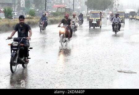 Hyderabad, Pakistan, 07. November 2022. Pendler fahren am Montag, den 07. November 2022, während des ersten Regenguß der Wintersaison in der Gegend von Teen Hatti in Karachi durch die Straße. Stockfoto