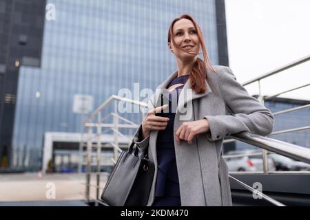 Rothaarige erfolgreiche Geschäftsfrau im Freien, Konzept für Karriereentwicklung und Unternehmenserfolg Stockfoto