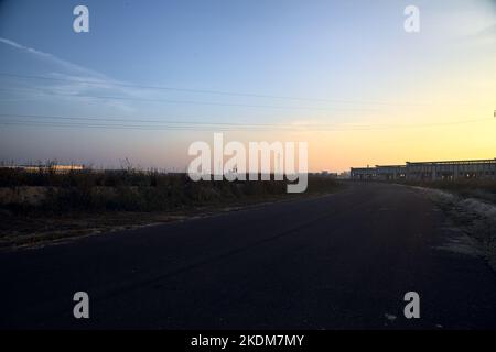 Leere Straße mit verlassenen Lagerhäusern und Pylonen bei Sonnenuntergang Stockfoto