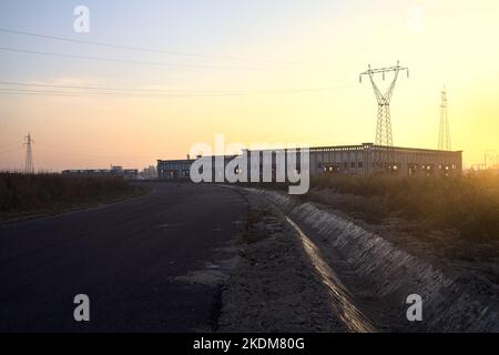 Leere Straße mit verlassenen Lagerhäusern und Pylonen bei Sonnenuntergang Stockfoto