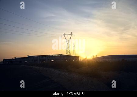 Leere Straße mit verlassenen Lagerhäusern und Pylonen bei Sonnenuntergang Stockfoto