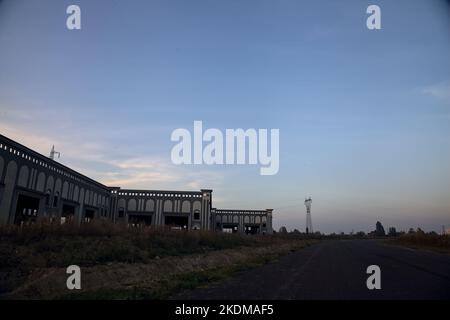 Leere Straße mit verlassenen Lagerhäusern und Pylonen bei Sonnenuntergang Stockfoto