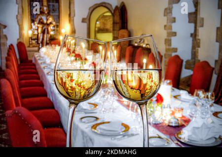 WEIHNACHTSWEIN LUXUS DINNER PARTY BANKETT UNTERHALTSAME ANLÄSSE Weißweingläser Toast im Vordergrund eines formellen Luxus Candlelight Bankett Dinner Party Tisch. Stockfoto