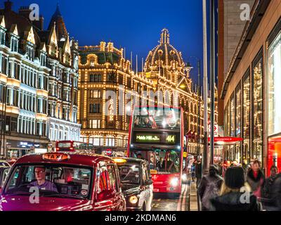 KNIGHTSBRIDGE VERKEHR WINTERVERKAUF Harrods Kaufhaus bei Nacht beleuchtet 'Verkauf' Schild Käufer roten Bus, Taxis, Blur Verkehr Brompton Road Knightsbridge London SW1 Stockfoto