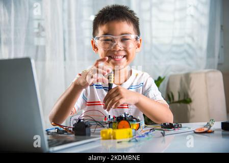 Asiatischer Junge, der zu Hause das Heimprojekt des Arduino-Roboters zusammenführt Stockfoto