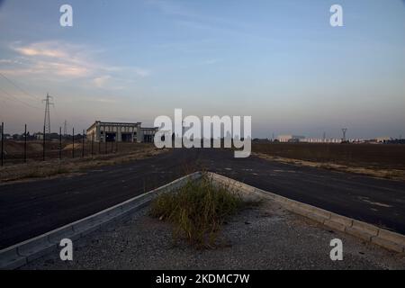 Gabelung in einer leeren Straße in einem Industriekomplex bei Sonnenuntergang Stockfoto