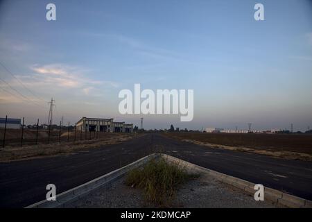 Gabelung in einer leeren Straße in einem Industriekomplex bei Sonnenuntergang Stockfoto