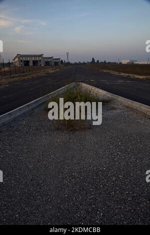 Gabelung in einer leeren Straße in einem Industriekomplex bei Sonnenuntergang Stockfoto