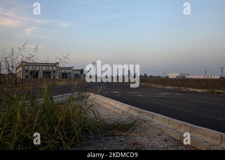 Gabelung in einer leeren Straße in einem Industriekomplex bei Sonnenuntergang Stockfoto