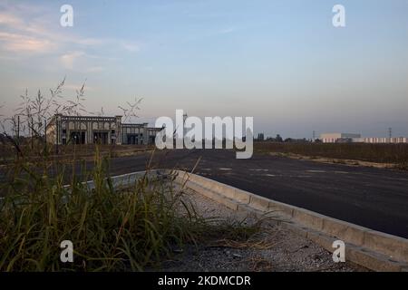 Gabelung in einer leeren Straße in einem Industriekomplex bei Sonnenuntergang Stockfoto