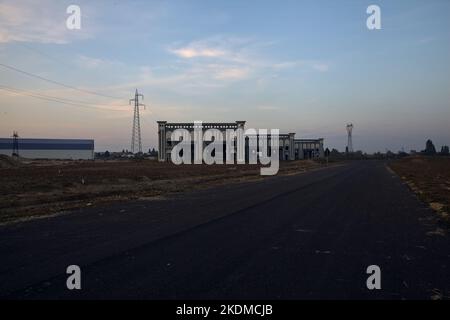 Leere Straße mit verlassenen Lagerhäusern und Pylonen bei Sonnenuntergang Stockfoto