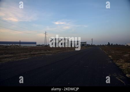 Leere Straße mit verlassenen Lagerhäusern und Pylonen bei Sonnenuntergang Stockfoto