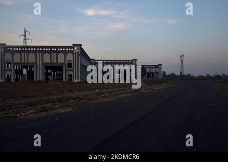 Leere Straße mit verlassenen Lagerhäusern und Pylonen bei Sonnenuntergang Stockfoto