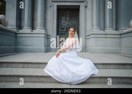 Braut mit Haltung, die vor einem Granitgebäude steht Stockfoto