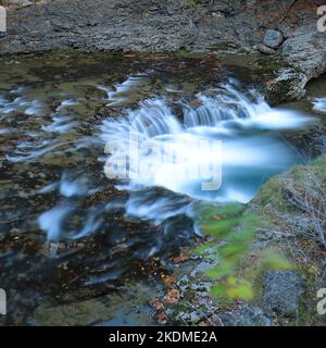 Kleiner Wasserfall, der ein kreisförmiges Becken im Fluss Arazas bildet, Nationalpark Ordesa y Monte Perdido, Huesca, Spanien. Das türkisfarbene Wasser fließt reibungslos. Stockfoto