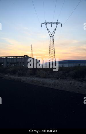 Leere Straße mit verlassenen Lagerhäusern und Pylonen bei Sonnenuntergang Stockfoto