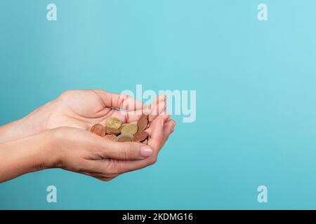Weibliche Hände mit Euro-Münzen auf hellblauem Hintergrund Stockfoto