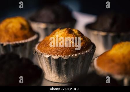 Frisch gebackene Muffins in Metallformen aus der Nähe in einer Bäckerei. Stockfoto