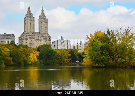 NEW YORK - 23 Okt 2022: Der Central Park Lake mit dem San Remo und seinen Zwillingstürmen und den Kenilworth Gebäuden im Hintergrund. Stockfoto