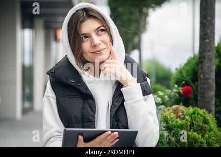 Attraktive junge Frau, die ein Tablet im Freien hält. Stockfoto