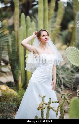 Braut umgeben von Kaktuspflanzen in einem Garten am späten Nachmittag Stockfoto