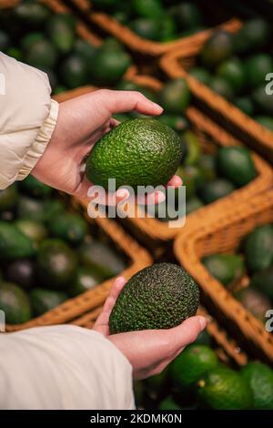 Eine Frau wählt eine Avocado in einem Lebensmittelgeschäft. Stockfoto