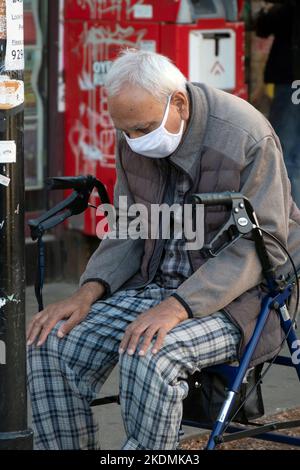 Ein älterer Muslim betet auf dem Diversity Plaza, während er auf seinem Spaziergänger sitzt. In Jackson Heights, Queens, New York City. Stockfoto