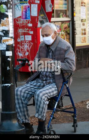 Ein älterer Muslim betet auf dem Diversity Plaza, während er auf seinem Spaziergänger sitzt. In Jackson Heights, Queens, New York City. Stockfoto