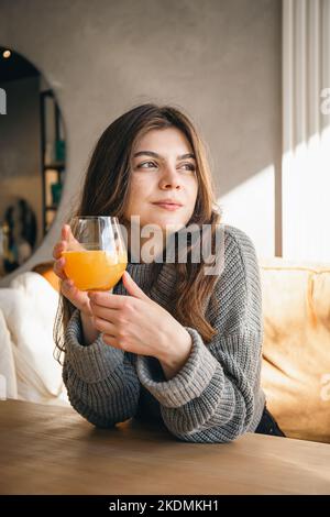 Attraktive junge Frau mit einem Glas Orangensaft in einem Café-Interieur. Stockfoto