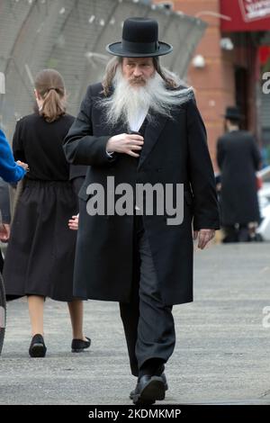 Ein chassidischer orthodoxer jüdischer Mann geht am Herbsttag mit seinem Bart und dem Peyot, der im Wind weht. In Brooklyn, New York. Stockfoto