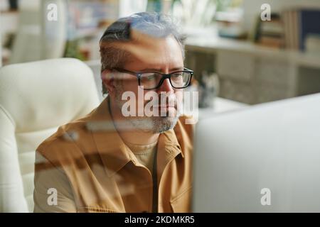 Zeitgemäßer Programmierer oder IT-Ingenieur, der vor dem Computer arbeitet und Informationen auf dem Bildschirm durchschaut Stockfoto