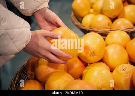 Grapefruit in weiblichen Händen, Früchte im Supermarkt kaufen. Stockfoto