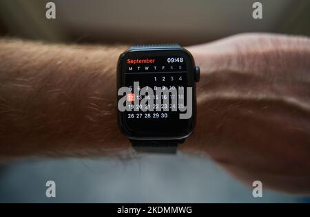 Eine quadratische Smartwatch auf der Hand eines Mannes. Kalender auf der Uhr Stockfoto