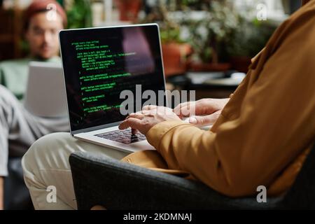 Reifer professioneller IT-Ingenieur, der neue Software entwickelt oder Daten auf einem Laptop decodiert, scren beim Tippen vor einem jungen Mitarbeiter Stockfoto